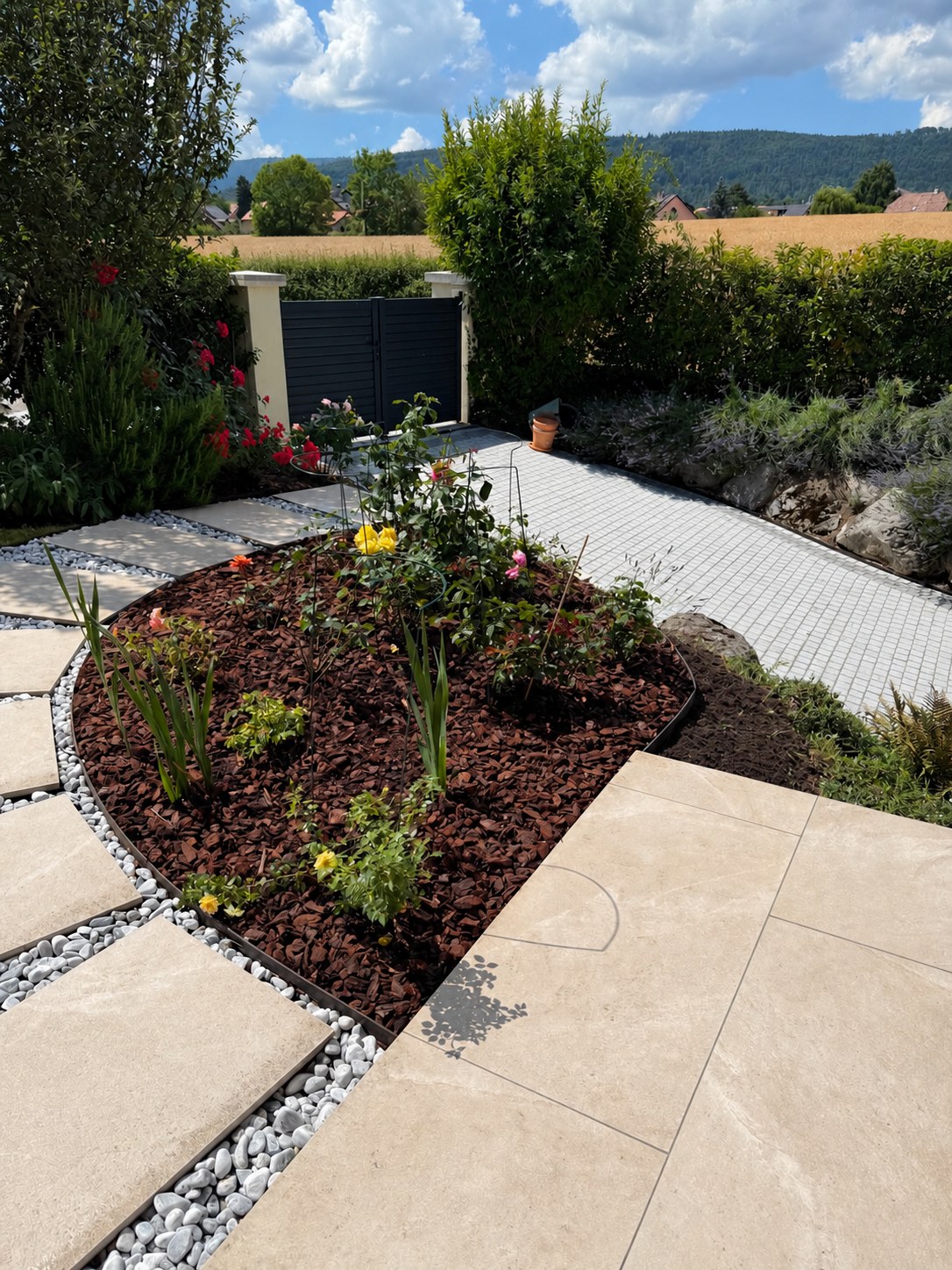 Massif décoratif créé dans un jardin avec plantations, paillage, dalles et galets blancs