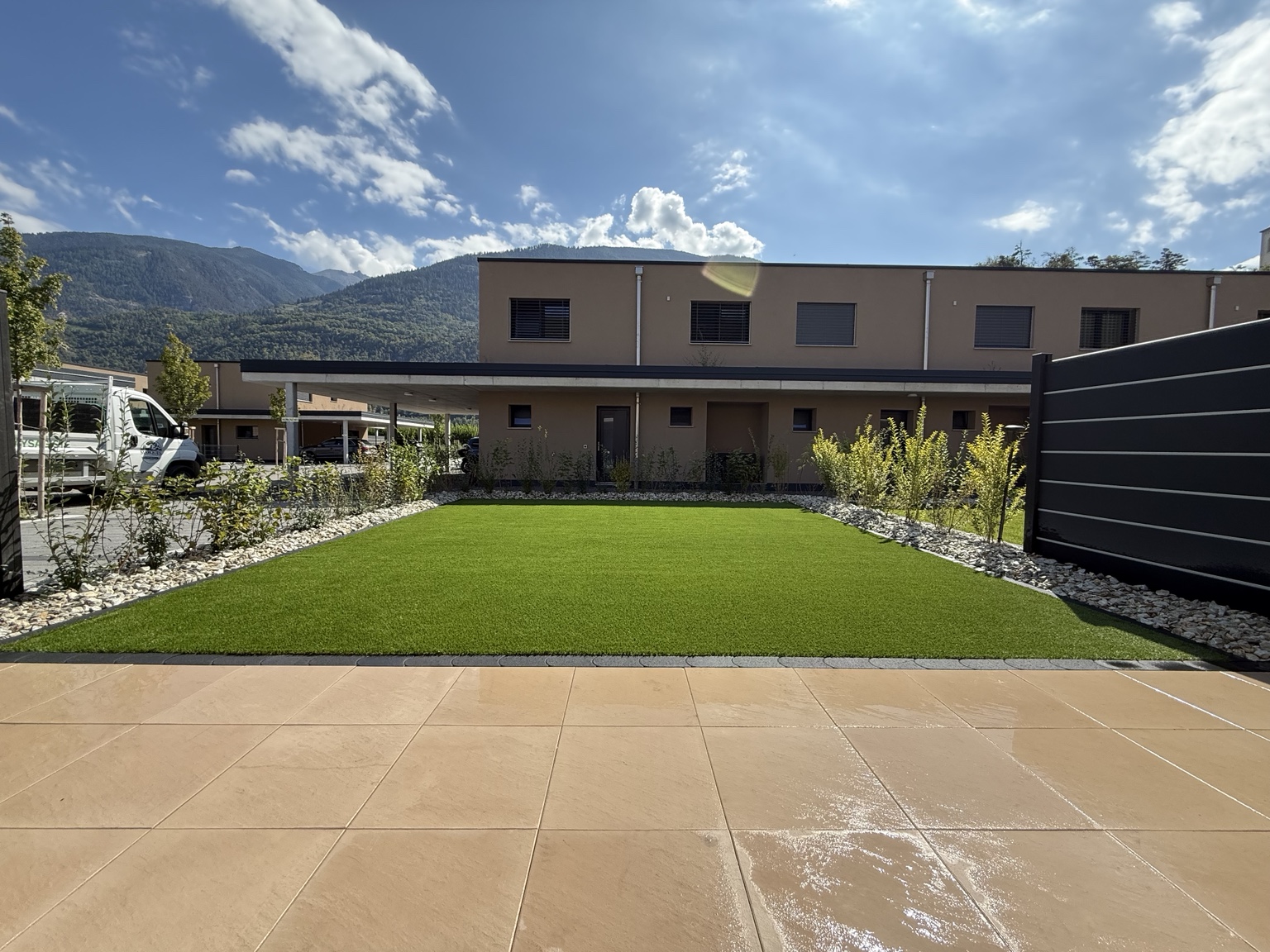 Jardin terminé avec gazon synthétique, plantations et pierres décoratives par Marques Paysagiste